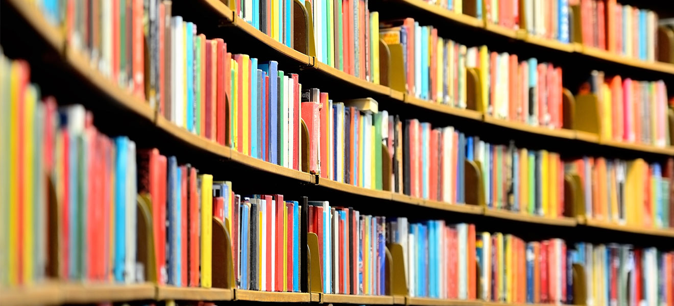 Foto: Bunte Buchrücken in einem nach innen gerundeten Bücherregal einer Bibliothek.