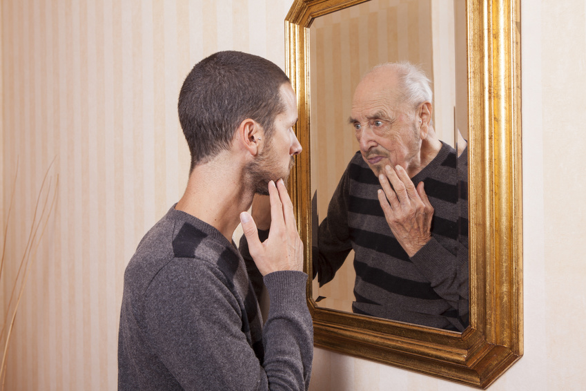 Junger Mann sieht sich älter im Spiegel
